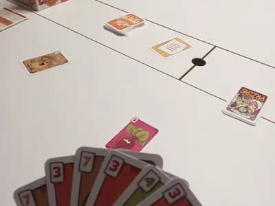 Karty z gry Zuuupa! w dłoni gracza podczas radosnej partii przy stole.