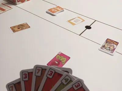 Karty z gry Zuuupa! w dłoni gracza podczas radosnej partii przy stole.